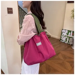 Lifestyle detail of a pink foldable drawstring bag with green shoulder straps worn by a model
