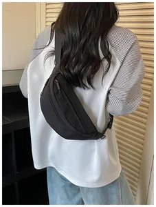 Rear view of a stylish black nylon waist bag worn by a person in high street outfit