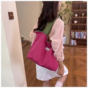 Back view of a model carrying a large pink drawstring shopping bag with green straps