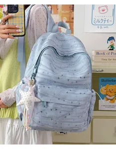 Detail of light blue tie-dye backpack with star pendant and embossed heart patterns.