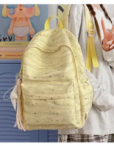 Detail view of a light yellow heart-pattern backpack with cute star charm accessory.