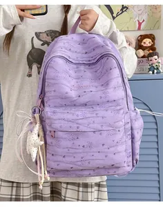 Detailed view of a purple tie-dye school backpack featuring butterfly patterns and a star charm