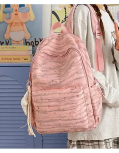 Detail of a pink tie-dye large capacity backpack worn by a student in a casual room.
