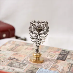 Sello de lacre de metal vintage con escudo de dragon y detalle de gema oscura.