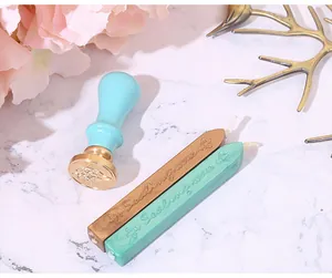 Macro shot of vintage blue wax seal stamp with gold and turquoise wax sticks on marble