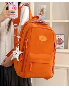 Detailed view of a bright orange water-repellent student backpack with a cute star charm
