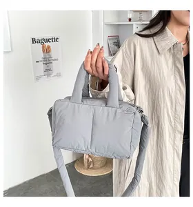 Detail of grey padded puffer handbag showing the soft quilted texture and top handle.