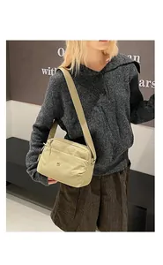 Modella indossa una borsa a tracolla beige in nylon in un ambiente interno informale