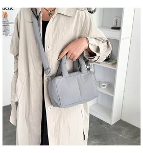 Close-up of a grey padded puffer tote bag carried by a model in a stylish minimal setting