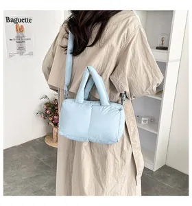 Light blue quilted puffer handbag worn with a beige trench coat for a casual look.