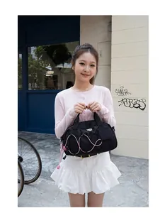 Asian model outdoors carrying a black outdoor sports crossbody bag with pink cord detail