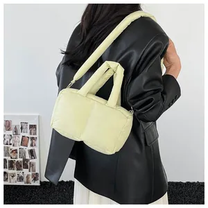Light yellow quilted puffer handbag with crossbody strap worn with a black jacket
