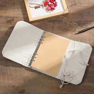 Vintage canvas loose-leaf notebook with kraft paper pages and string tie on wooden desk.