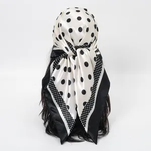 Close-up of a stylish white and black polka dot satin headscarf tied on a mannequin.