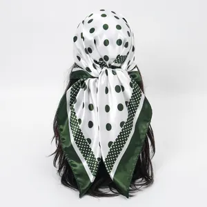 Back view of a green and white polka dot silk head scarf on a mannequin