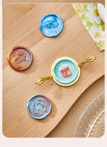 Molde metálico dorado para sellos de cera con mangos decorados en fondo de madera