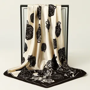 Close-up of elegant satin square scarf with black rose floral pattern on cream base