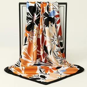 Detail of luxurious floral satin square scarf with vibrant orange and black print