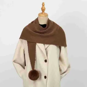 Dettaglio dello scialle lavorato a maglia marrone con pompon su un manichino