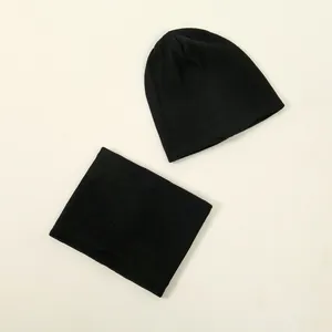 Flat lay of black ribbed knit beanie and matching neck warmer set on a plain background.