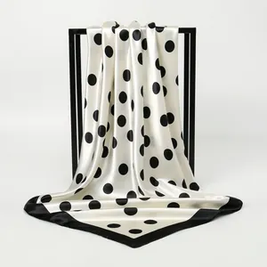Detailed view of cream satin square scarf with bold black polka dots and border
