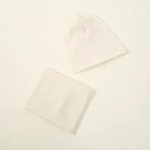 Flat lay view of a white knitted beanie hat and matching neck warmer scarf set