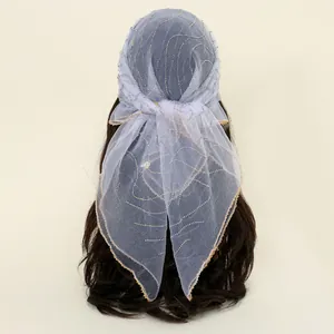 Close-up detail of a sheer light blue mesh headscarf with sparkling hot-fix rhinestone patterns.