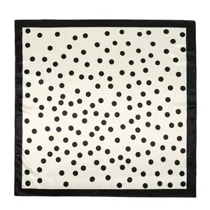Close-up detail of a classic black and white polka dot pattern satin square scarf