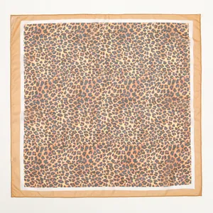 Detailed flat lay of an elegant leopard print chiffon square scarf with a tan border