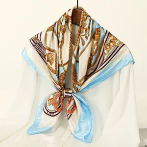 Elegant blue and gold chain print satin square scarf displayed on a white shirt