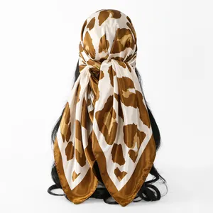 Detailed view of a leopard print satin square scarf tied as a fashionable headwrap.
