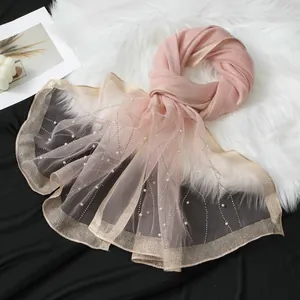 Detail of a pink organza scarf with rhinestones, pearls and golden glittery edges
