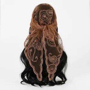 Detailansicht eines braunen Dreieckstuchs mit Paisley-Stickerei aus Spitze.