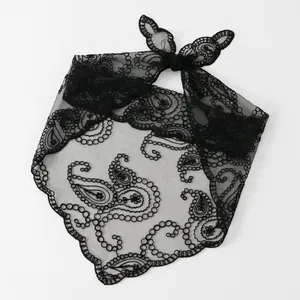 Nahaufnahme der schwarzen Paisley-Stickerei auf einem transparenten Spitzenschal