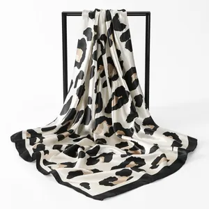 Detailed macro view of a luxury satin leopard print square scarf draped elegantly on a frame