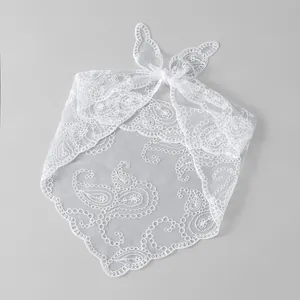 Detailaufnahme von weißem Spitzenkopftuch mit Paisley-Stickerei und Schleifendetail