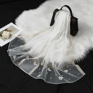 Vue détaillée d'une écharpe élégante en organza blanc avec perles et broderies papillons