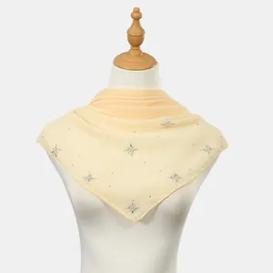 Detailed view of a light yellow chiffon square scarf with star-shaped rhinestone patterns.