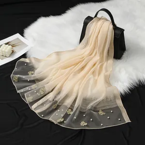 Détail d'une écharpe élégante en organza avec des broderies papillons et des perles blanches