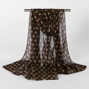 Detailed view of brown chiffon scarf with mint green polka dot pattern draped on rod