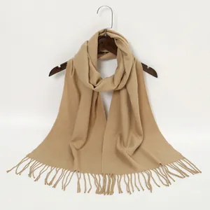Detailed close-up of a camel-colored cashmere-like scarf with elegant fringe tassels