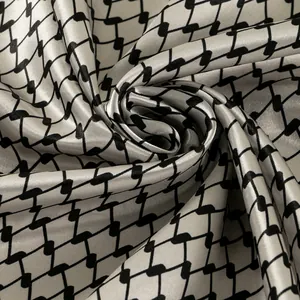 Macro detail of soft satin square scarf featuring a stylish black geometric pattern on silver