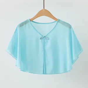 Detail view of a light blue chiffon shawl with a button closure on a wooden hanger.
