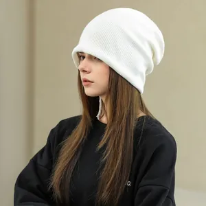Close-up view of a cozy white knitted beanie hat for women, perfect for winter warmth.