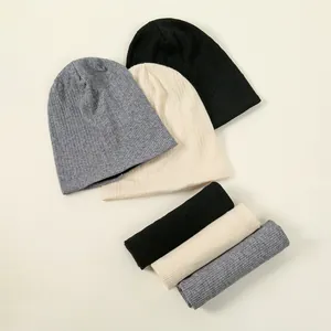 Overview of knitted beanie hats and neck warmers in black, cream, and grey colors