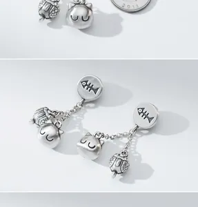 Close-up of retro matte 99 silver cat and fish bone charms for DIY jewelry making.
