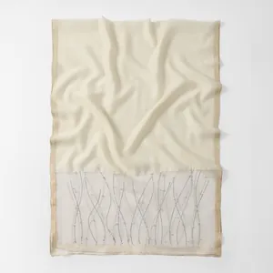 Detailed view of cream organza scarf with rhinestone waves and pearl accents