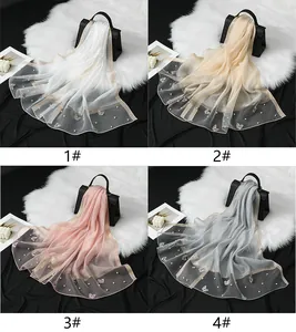 Détail de quatre écharpes en organza avec broderies papillons et perles en divers coloris.