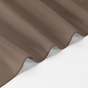 Gros plan sur le tissu du châle en mousseline marron montrant un drapé élégant