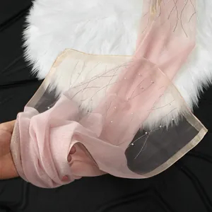 Close-up of elegant pink organza scarf with rhinestone wave pattern and pearl beads